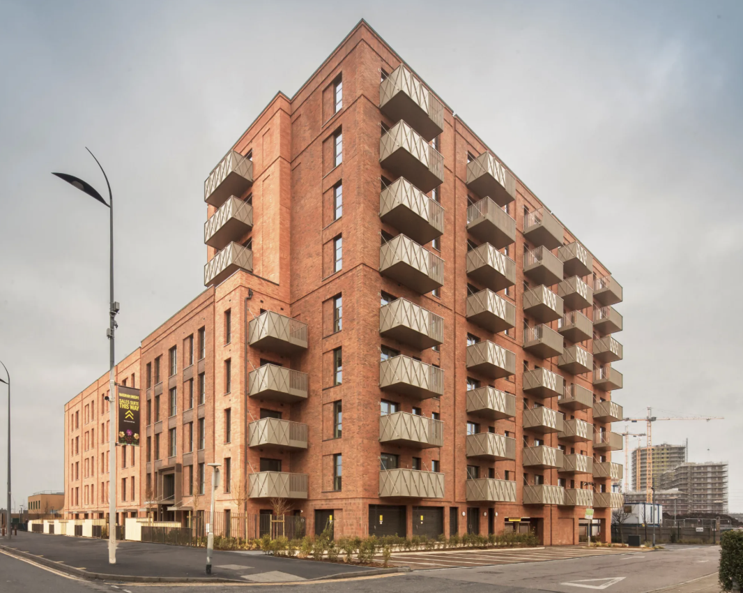 Completed Transport House residential development in Dagenham, showing the red brick elevation and projecting metal balconies